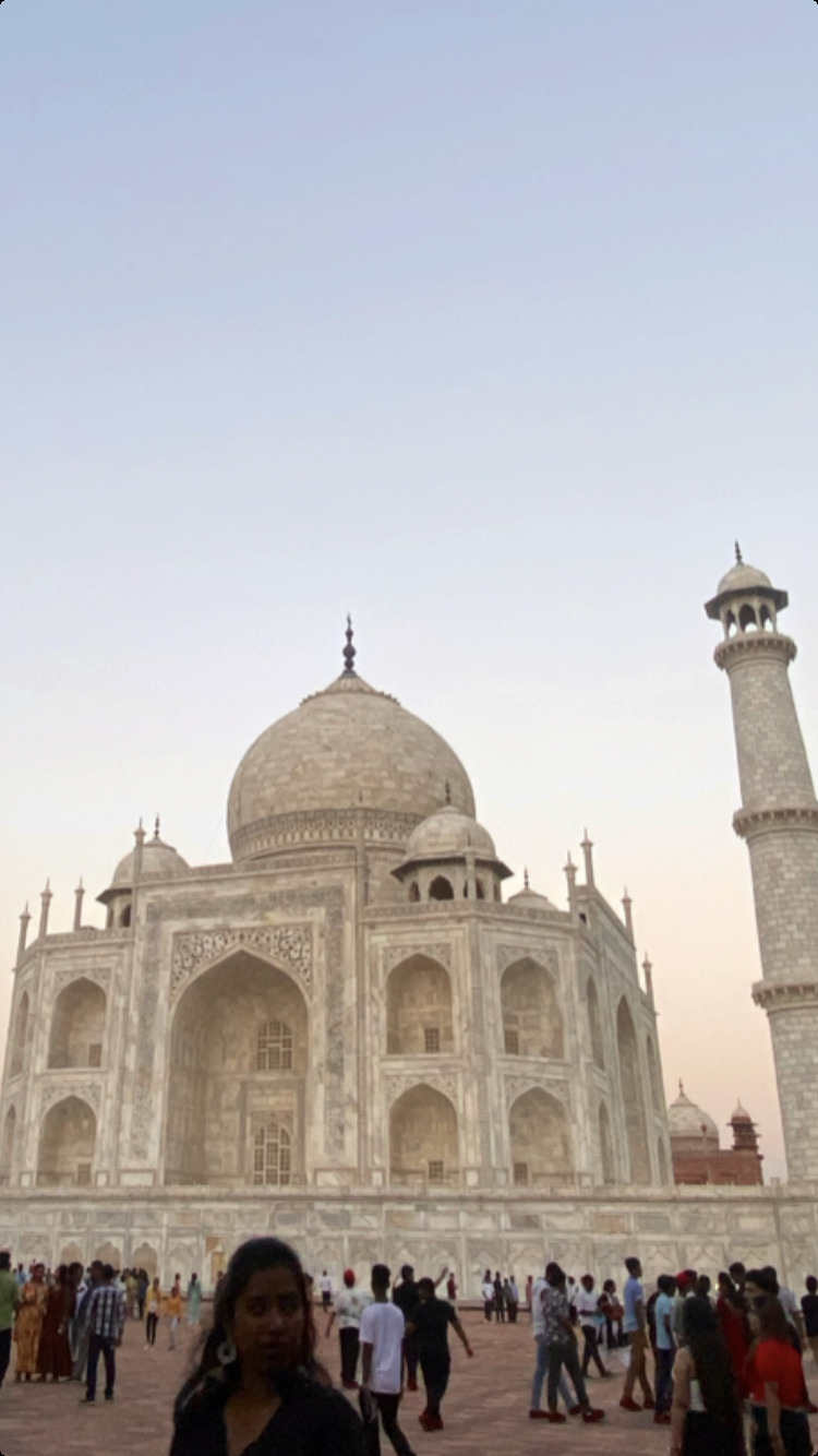 The Taj Mahal at dusk, with people crossing the forecourt