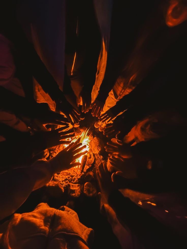 Hands reaching towards a fire at night